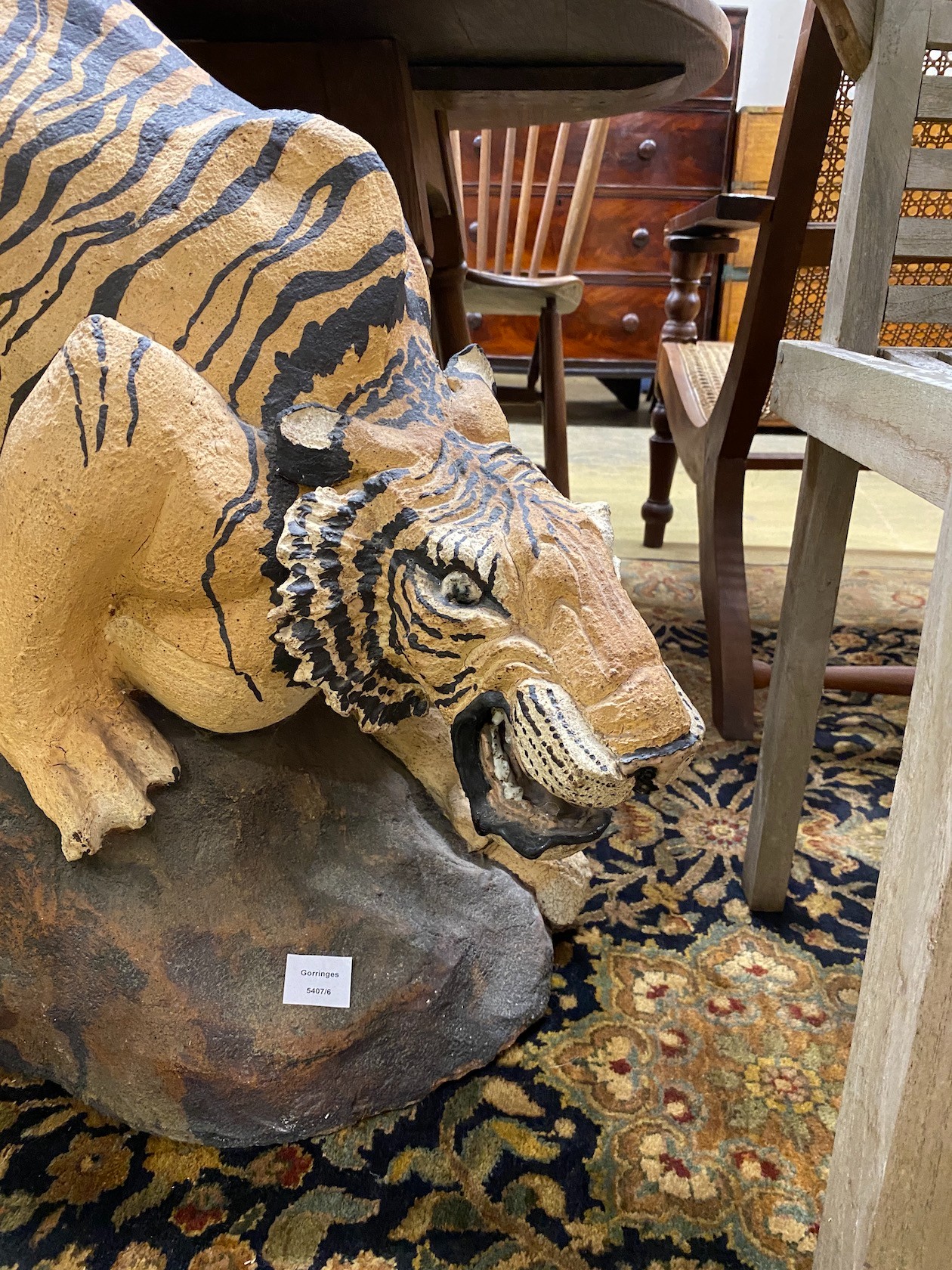 A painted stone garden ornament of a crouching tiger, tail detached, height 75cm